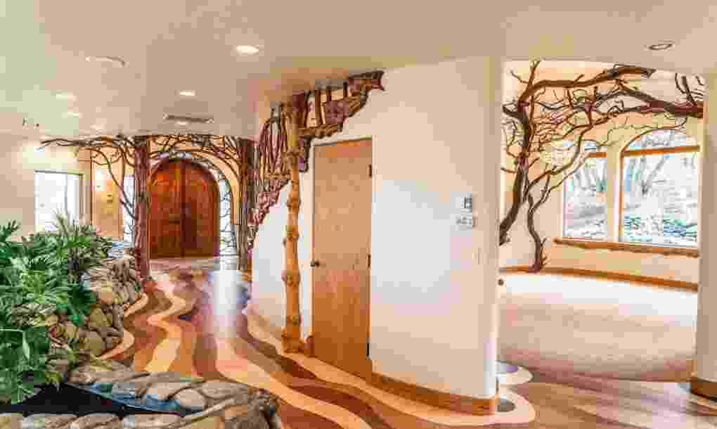Lantai parquet berwarna cokelat dan sungai yang dihiasi bebatuan alam memberi kesan alami pada ruangan